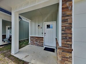 Ein Haus mit Veranda, einer Wand aus Stein, einer weißen Tür mit der Nummer 13 und einem Briefkasten.