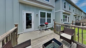 Eine Terrasses mit Grill, Gartenmöbeln und Holzgeländer.