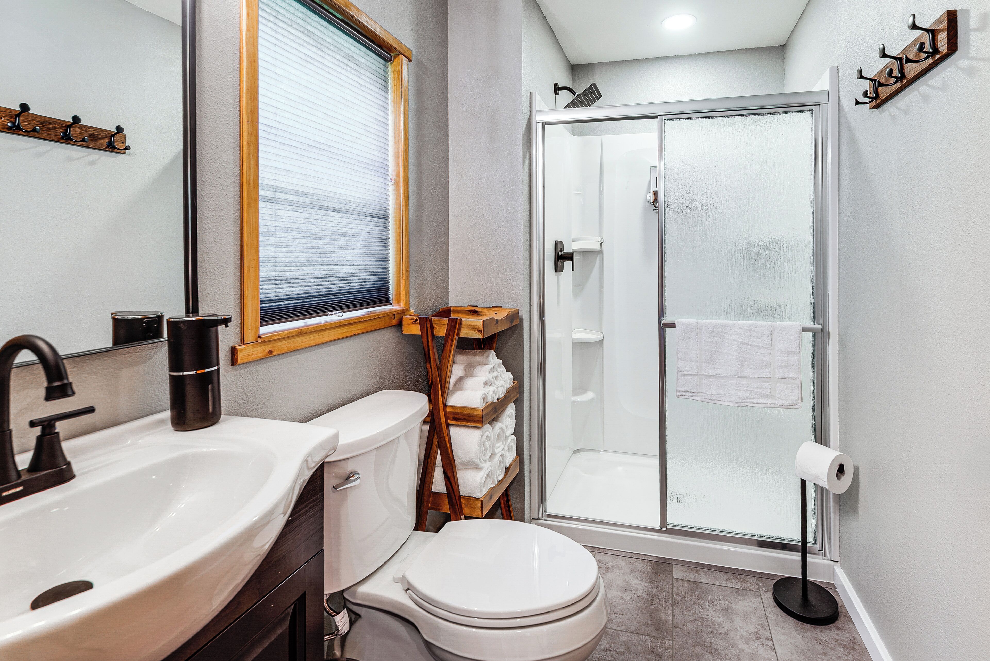Bagno con lavandino, water, doccia e finestra.