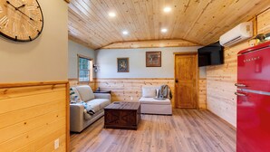 Ein gemütlicher Raum mit Holzwänden und -decke, einer Couch, einem kleinen Tisch und einem roten Gerät.