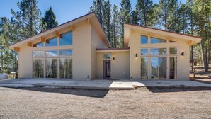 A modern two-story house with large windows, a flat roof, and a gravel driveway.