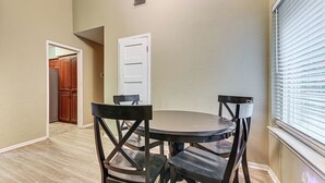 A dining area with a round table and four chairs, a white door, and a window with blinds. - 2 Mi to Denton Square! Spacious Home w/ Backyard (Denton)