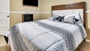 A bedroom with a bed, a TV mounted on the wall, and a door. - 2 Mi to Denton Square! Spacious Home w/ Backyard (Denton)