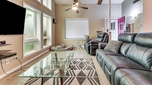 A living room with a glass coffee table, leather sofa, and a ceiling fan. - 2 Mi to Denton Square! Spacious Home w/ Backyard (Denton)