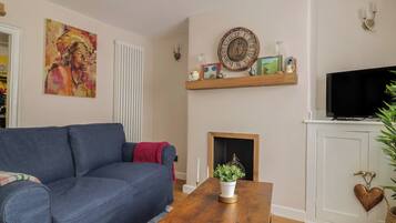 A living room with a blue sofa, a wooden coffee table, a fireplace, a television, and a painting on the wall.