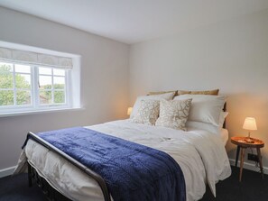 A bedroom with a bed, a window, and a bedside lamp. - No. 6 (Bridport)