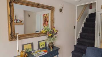 A staircase with a dark carpet, a blue sofa, a decorative mirror, and a console table with a vase of flowers and various items.