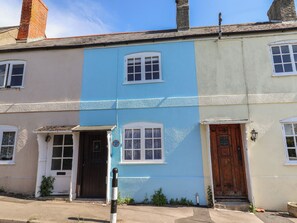 A row of two-story houses with distinct color patterns, a visible number on the blue house, and a traditional wooden door. - No. 6 (Bridport)