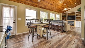 A spacious kitchen with a wooden ceiling, a dining area with a round table and bar stools, and a fireplace. - Dock, Deck & Sunsets! Little Bungalow on Lake Mary (Twin Lakes)