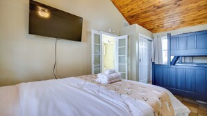 A bedroom with a bed, a TV mounted on the wall, a wooden ceiling, and a blue cabinet. - Dock, Deck & Sunsets! Little Bungalow on Lake Mary (Twin Lakes)