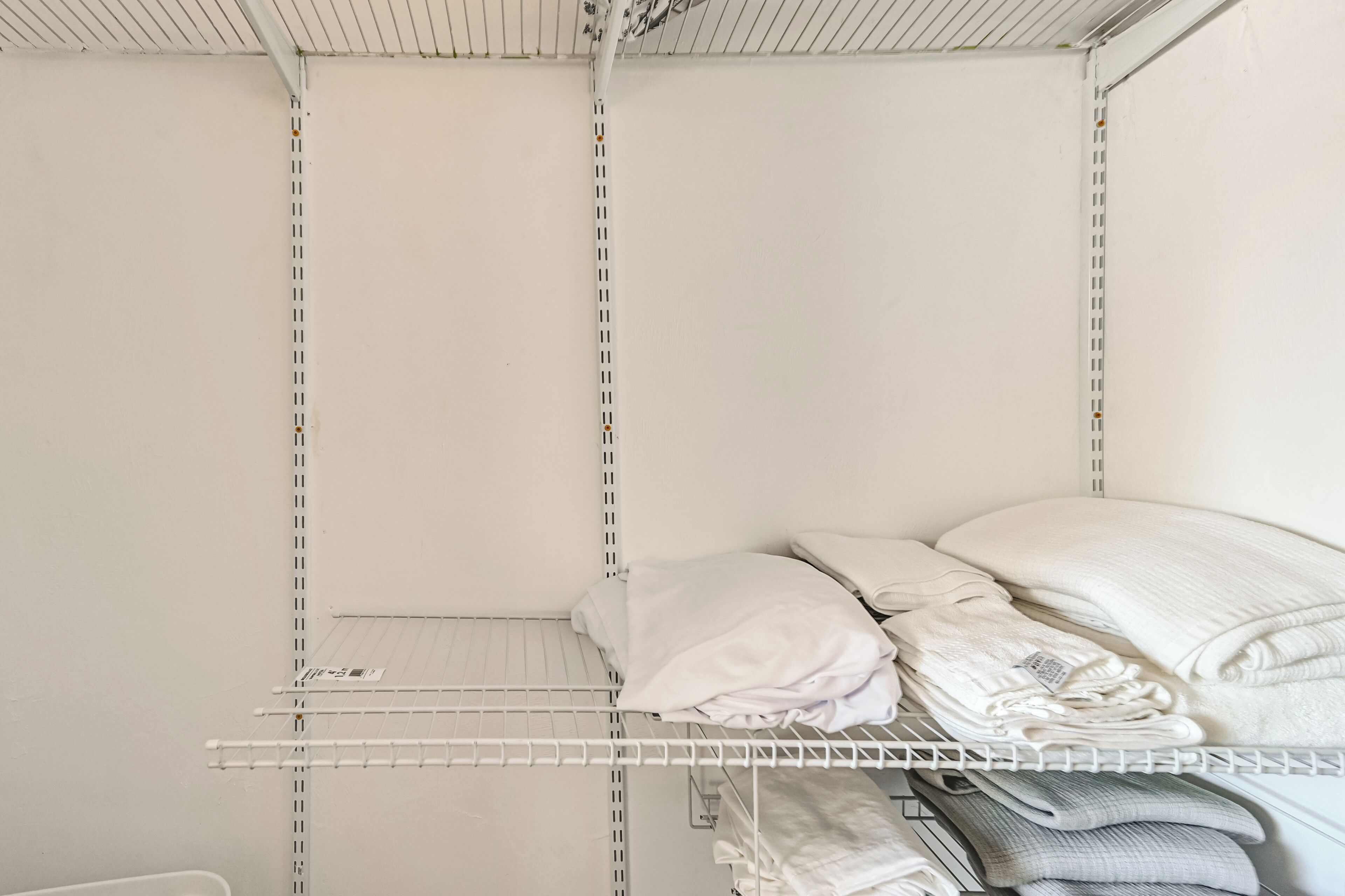A storage closet with metal shelving, some folded towels, and a white wall.