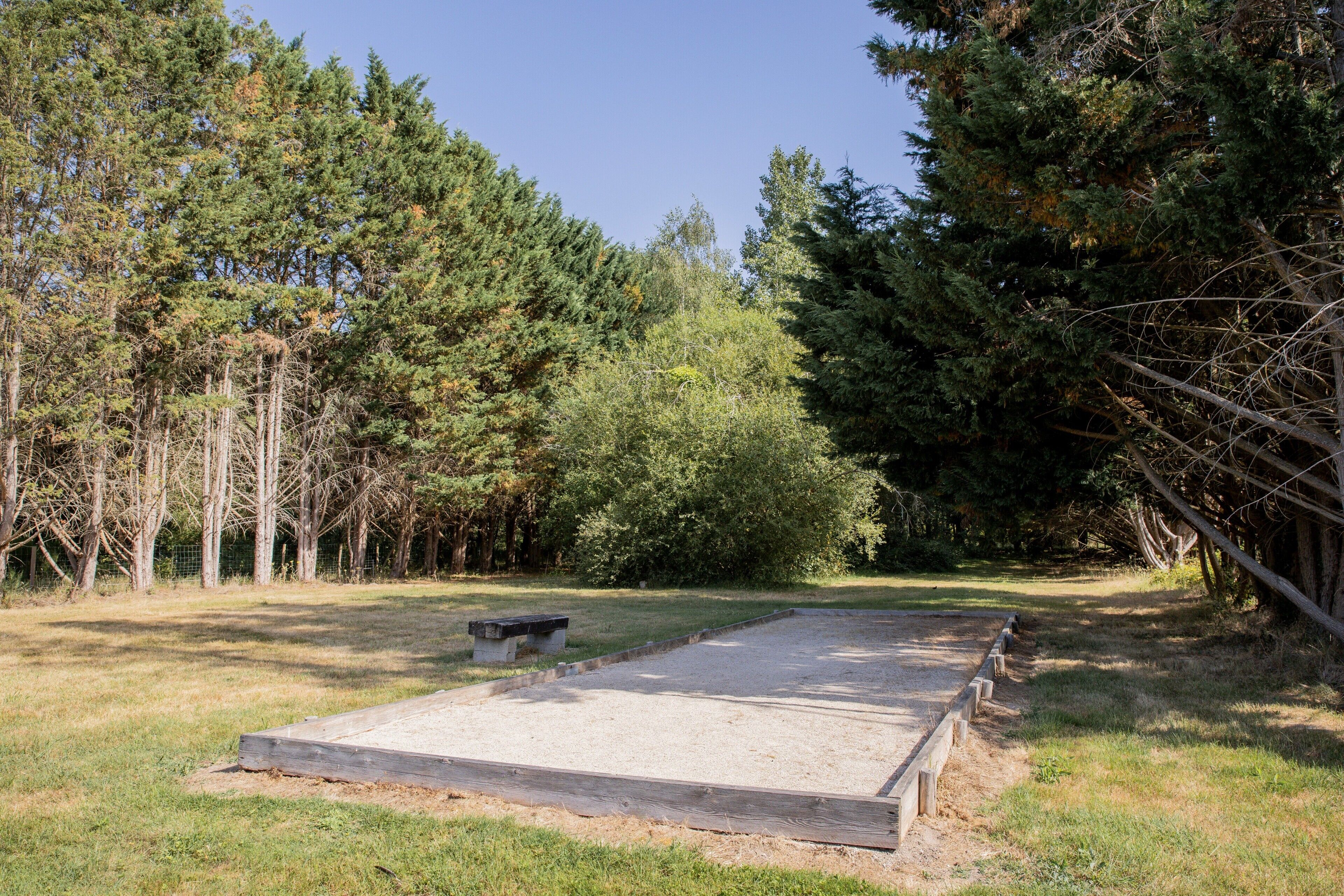 A concrete platform with a bench, surrounded by dense trees and a clear sky.
