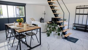 A modern living space with a dining area, a staircase, and a sofa. - Les2toits Loft with Pool in the Heart of Sologne (Pruniers-en-Sologne)