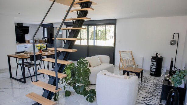A modern living space with a spiral staircase, a dining area, a sofa, and a coffee table. - Les2toits Loft with Pool in the Heart of Sologne (Pruniers-en-Sologne)