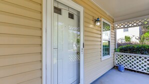 Una casa con puerta blanca, ventana y porche con celosía blanca.