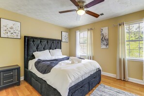 A bedroom with a bed, ceiling fan, artwork, window with curtains, and a nightstand. - 3 Mi to The Village! Family Home in Stone Mountain (Stone Mountain)