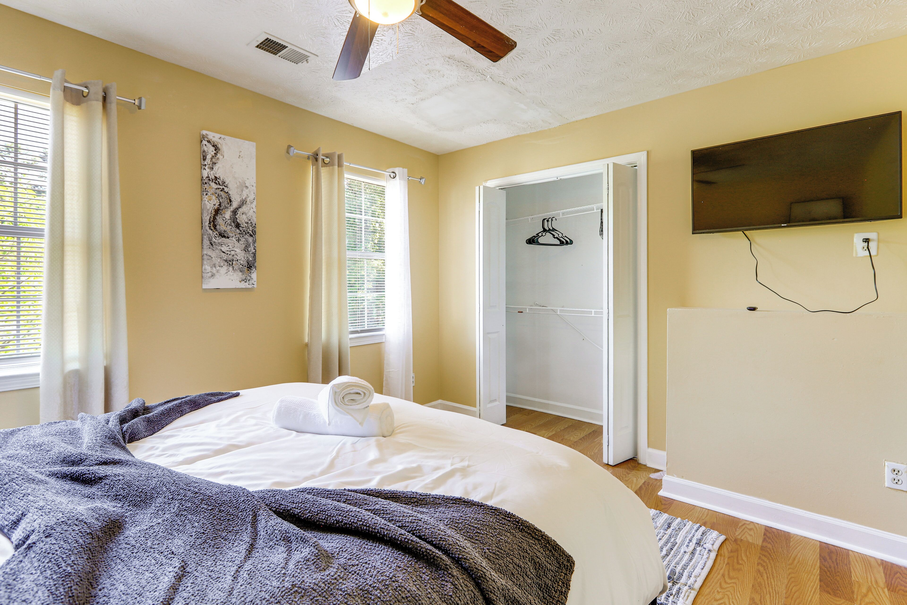 Une chambre avec un lit, un ventilateur de plafond, une douche et un téléviseur fixé au mur.