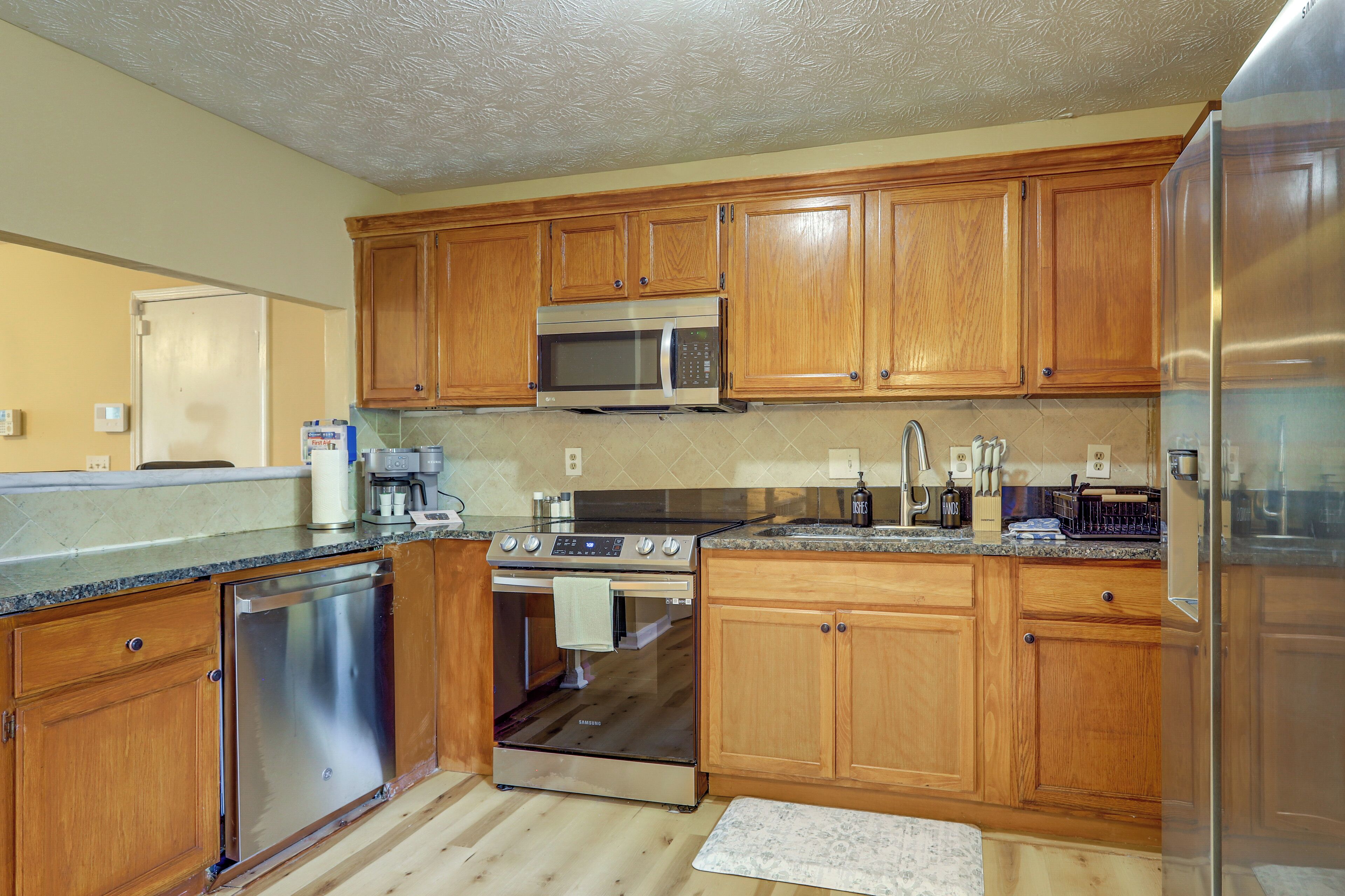 A kitchen with wooden cabinets, stainless steel appliances, and a granite countertop.
