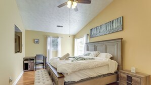 Un dormitorio con cama, escritorio, silla, banco, mesita de noche y ventilador de techo.