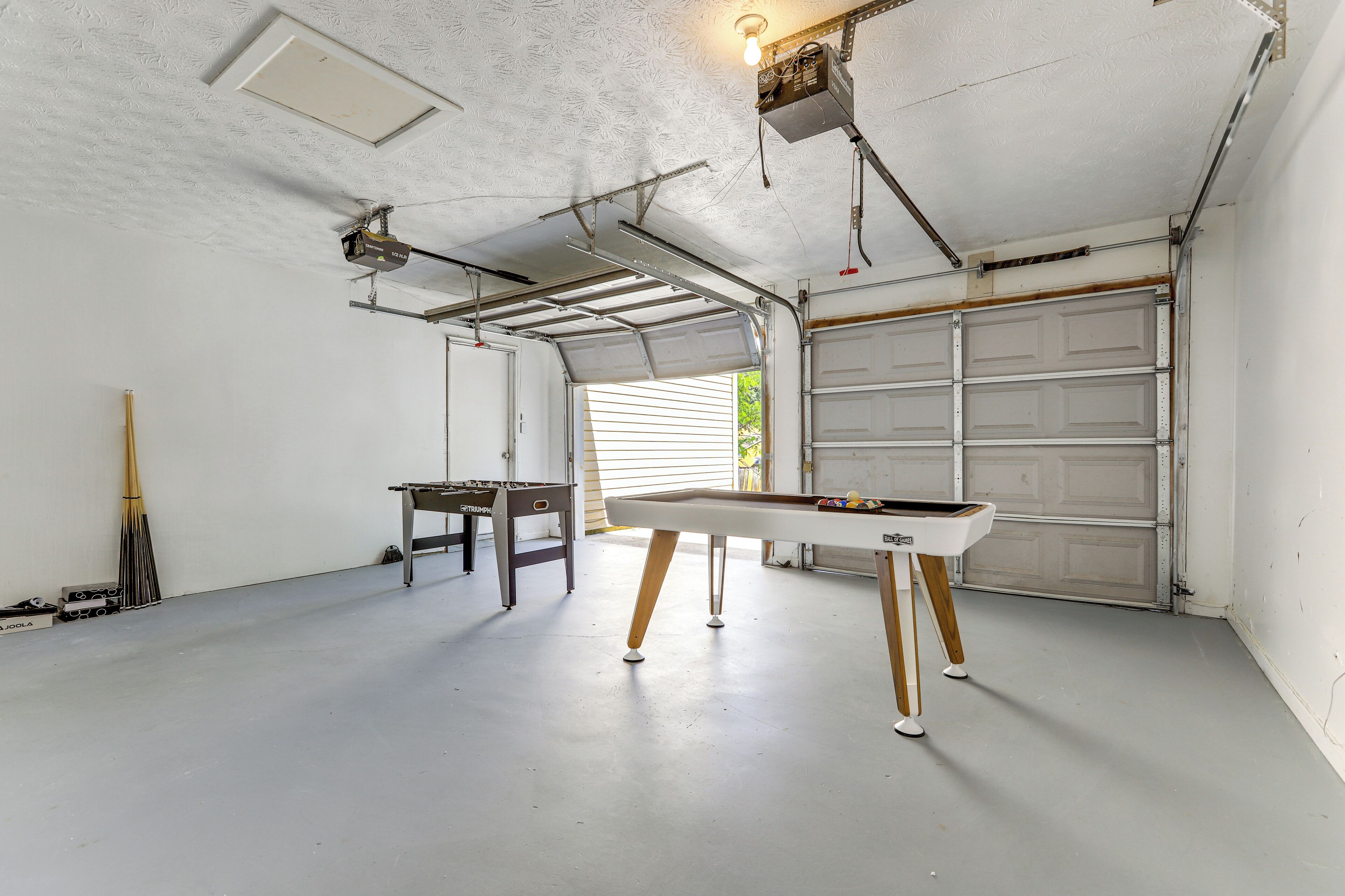 A garage with a pool table, a ceiling fan, and a garage door.
