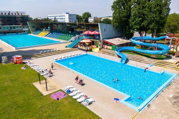 A swimming pool with adjacent seating and a water slide.