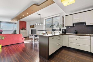 A modern kitchen with a central island, white cabinetry, and a red accent wall.