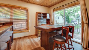 Un intérieur en bois comprenant un coin repas, des tabourets de bar, un meuble en bois et une grande fenêtre.