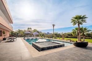 Una piscina con jacuzzi, mobiliario exterior y un pabellón.