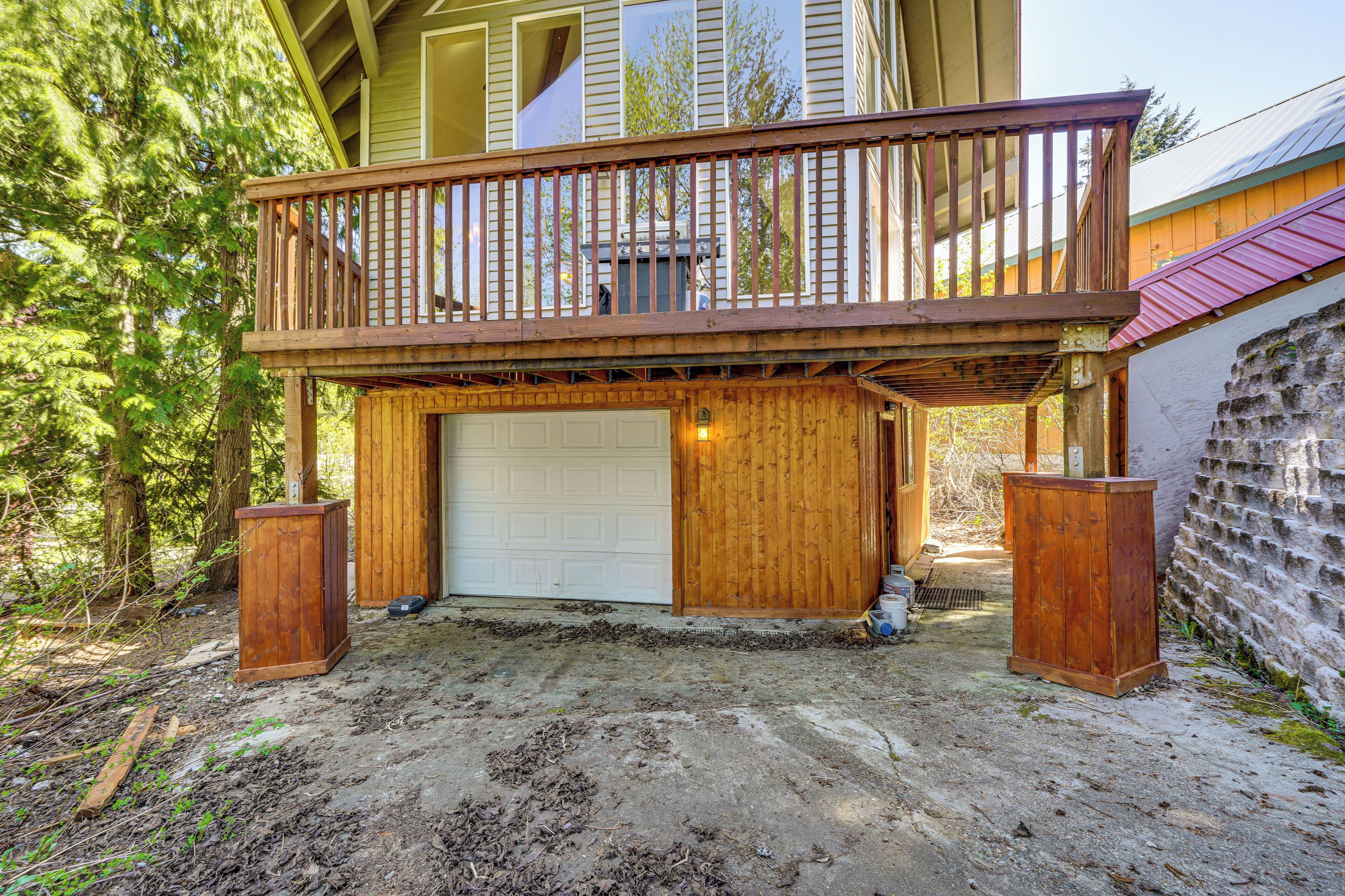 A two-story house with a wooden deck, a garage, and a stone wall.