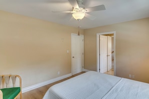 Ein Schlafzimmer mit einem Bett, einem Deckenventilator und einer Tür zu einem anderen Raum.