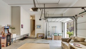 A spacious garage with a couch, a table, and a gaming machine. - Amazing Mtn & City Views! Simi Valley Hideaway (Simi Valley)