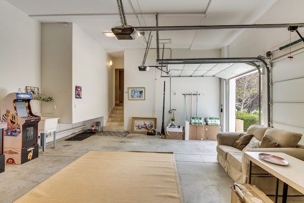 A spacious garage with a couch, a table, and a gaming machine. - Amazing Mtn & City Views! Simi Valley Hideaway (Simi Valley)
