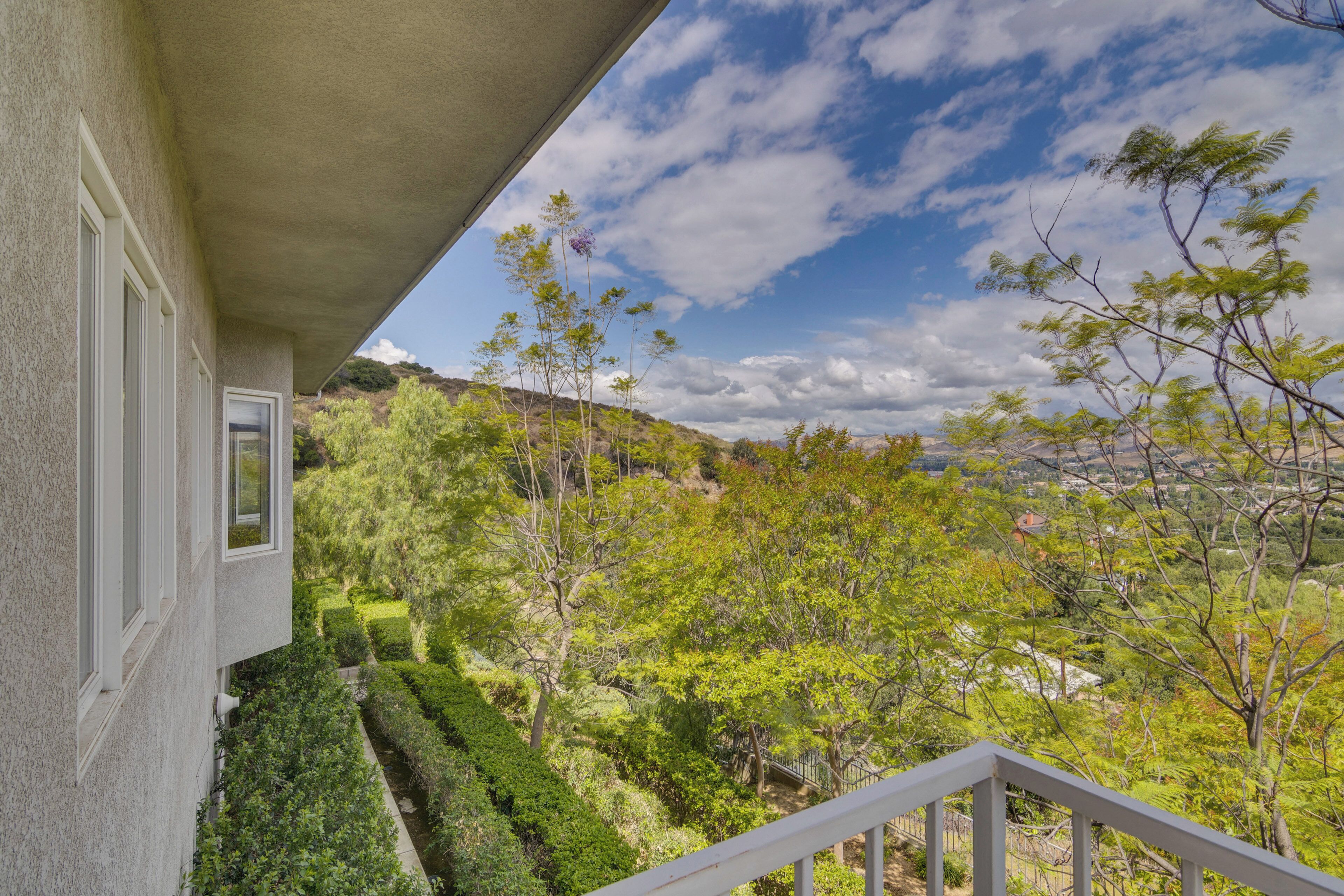 A balcony with a view of a landscaped garden and trees.