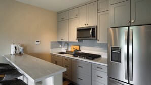 Una cocina moderna con electrodomésticos de acero inoxidable, encimera blanca y muebles de cocina de tonos claros.