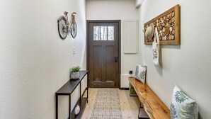 A hallway with a wooden bench, a door, a wall-mounted bicycle, and a decorative wall piece. - Long Lake Cabin w/ Dock: Fish & Hike! (Akeley)