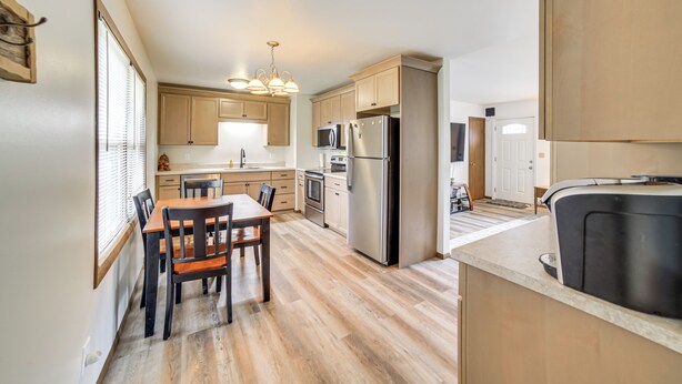 A modern kitchen with wooden cabinets, stainless steel appliances, and a dining area with a table and chairs. - Explore the Upper Peninsula! Marquette Home (Marquette)