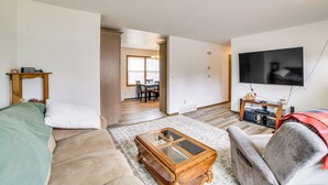 A living room with a sofa, armchair, coffee table, and TV. - Explore the Upper Peninsula! Marquette Home (Marquette)
