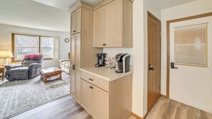 A compact living space with a kitchenette, a sofa, a coffee table, and a window with blinds. - Explore the Upper Peninsula! Marquette Home (Marquette)