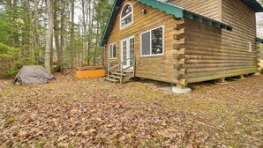 A wooden cabin with a green roof, a covered porch, and a staircase leading to the entrance.