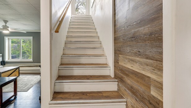 A staircase with white steps leading to a landing, adjacent to a wooden wall.
