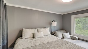 A bedroom with a bed, pillows, a bedside lamp, and a window with a view.