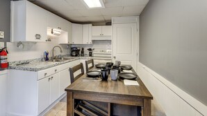 A kitchen with white cabinets, a marble countertop, and a dining table set with plates and cups.