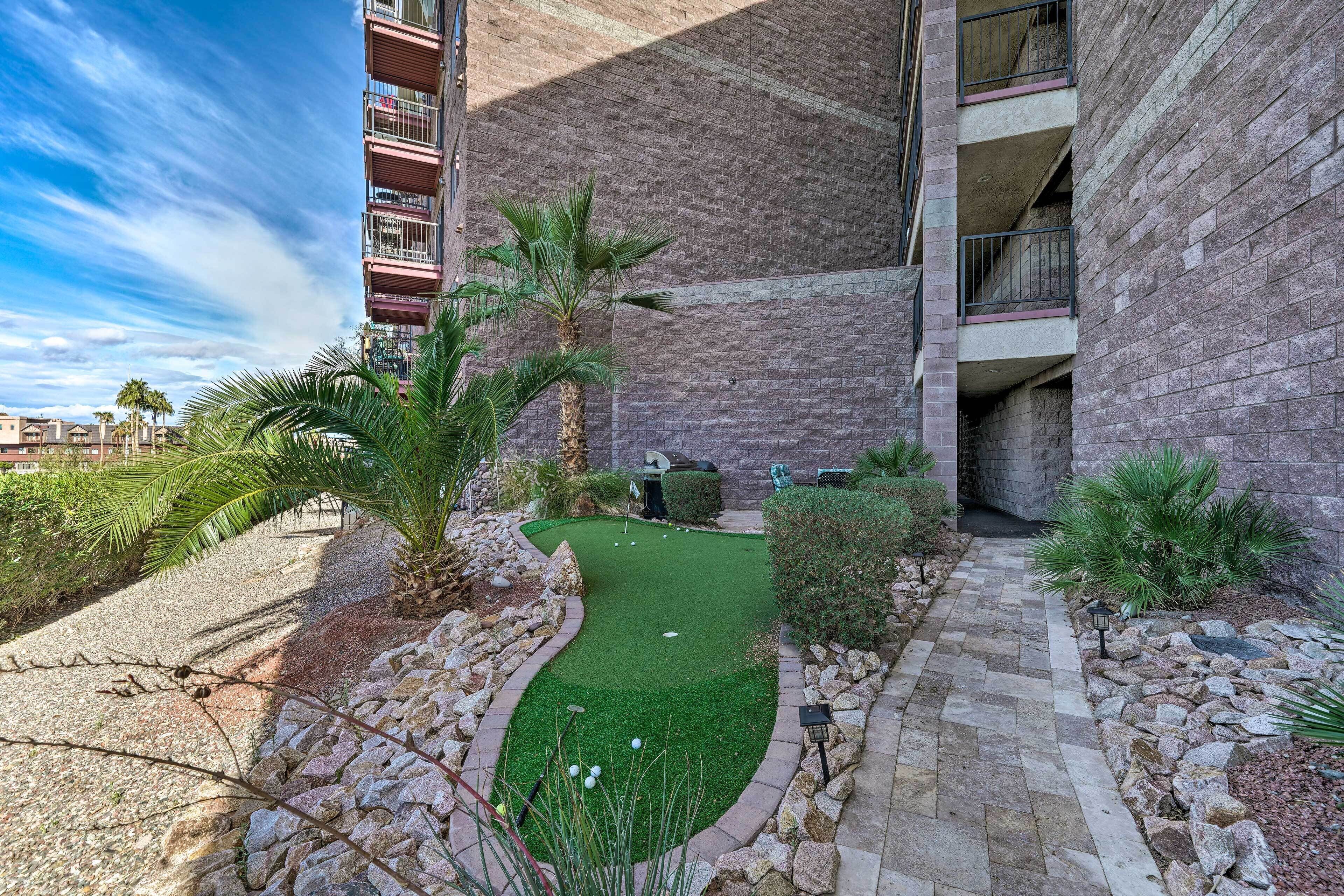 A courtyard with a putting green, palm trees, and a stone pathway.