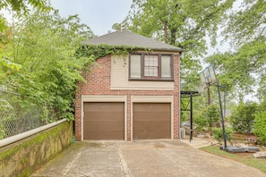 A two-story building with a garage, a basketball hoop, and a small garden area. - Birmingham Apt Near Amphitheater w/ Shared Patio (Birmingham)