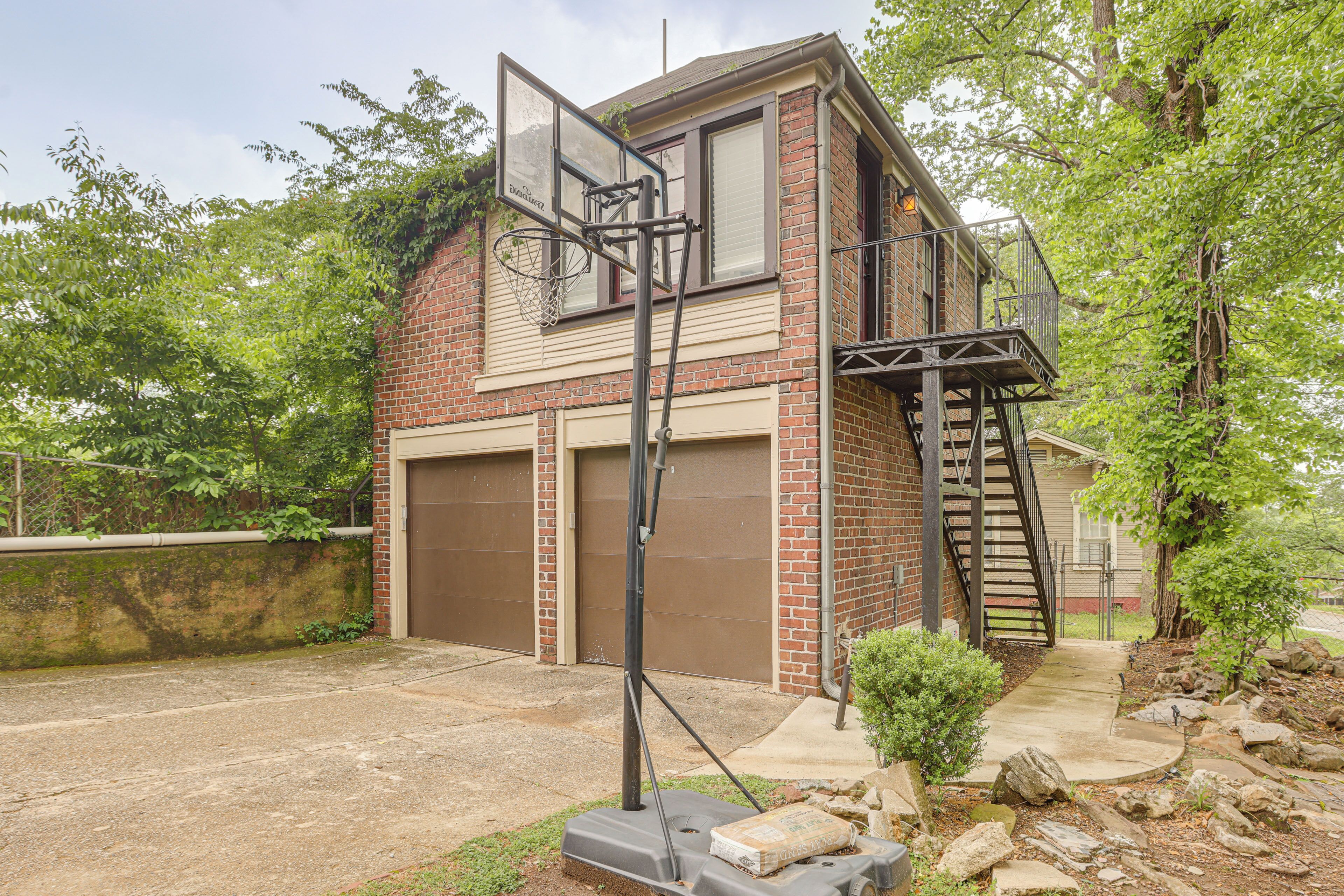 A two-story brick house with a garage, a basketball hoop, and a small staircase leading to an upper level.