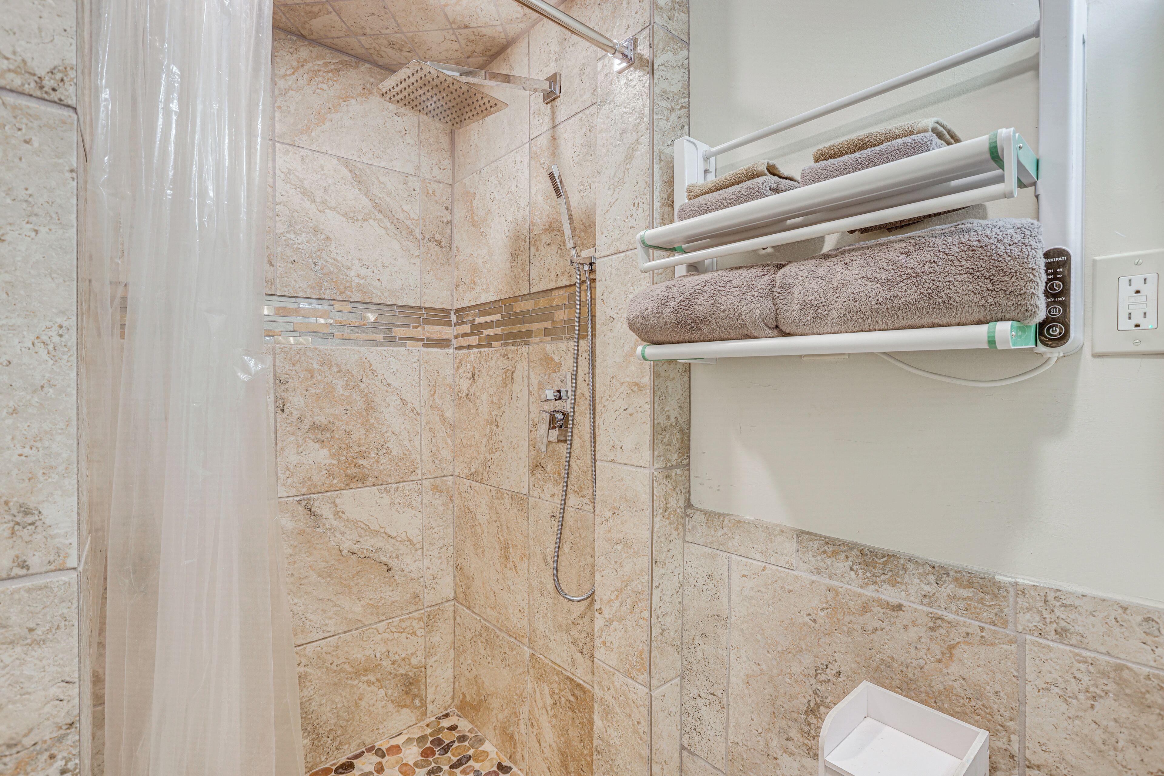 A bathroom with a shower, a towel rack, and a small white box on the floor.