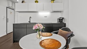 Een moderne keuken met witte kastjes, een koffieapparaat en een bloemenvaas op het eiland.