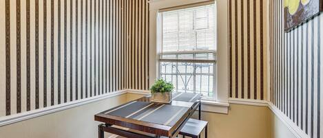 Une pièce d’angle avec une fenêtre, une table avec des bancs et des murs à rayures.