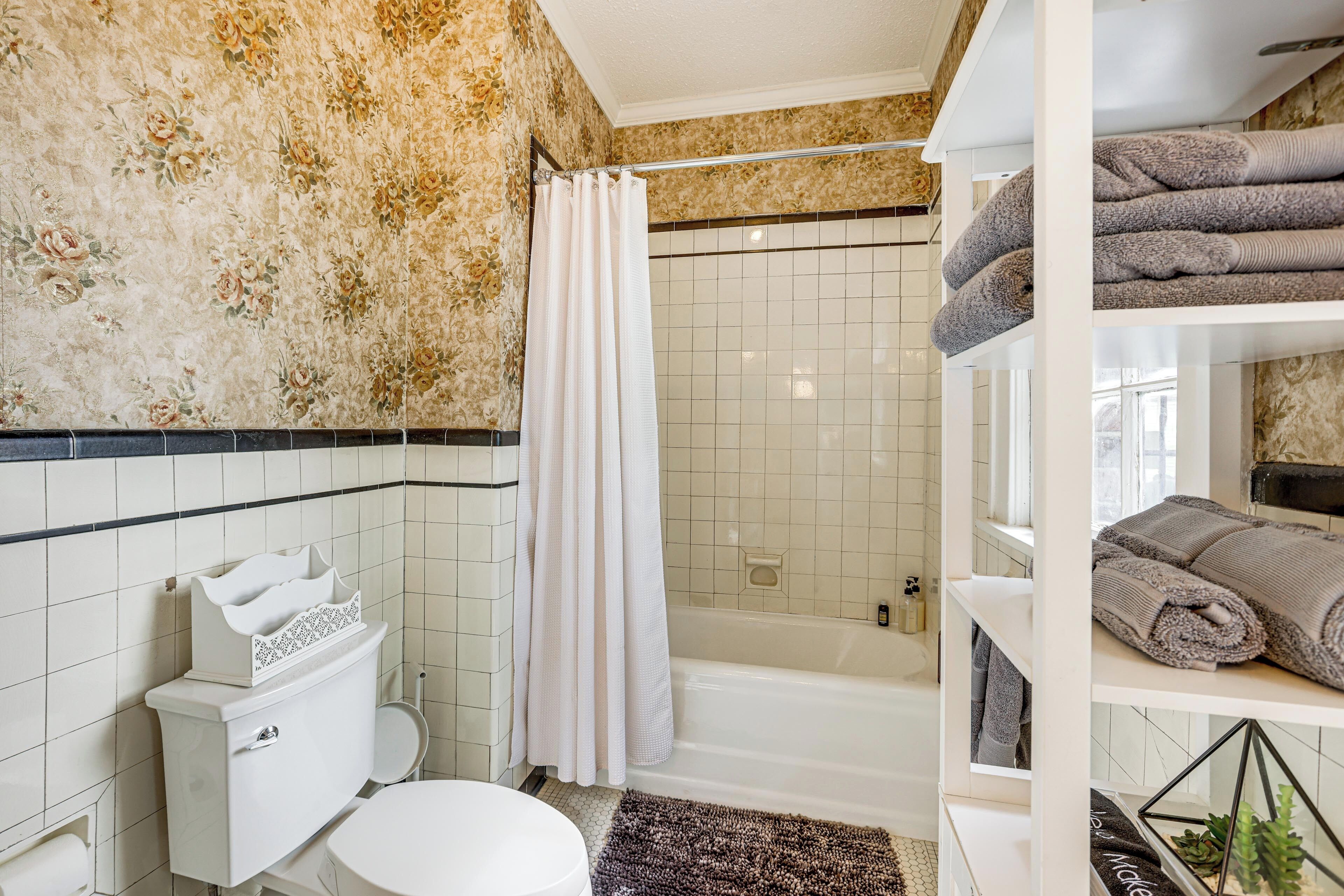 A bathroom with a toilet, shower, and shelves with towels.