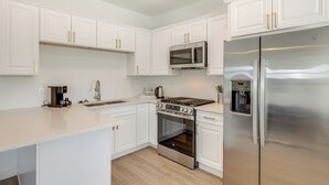 A modern kitchen with white cabinetry, stainless steel appliances, and a beige countertop. - Easy Dtwn Access! Prime PHX Stay For Couples (Phoenix)